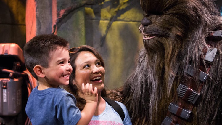 A young male Guest and his mother smiling while they meet Chewbacca at Disney's Hollywood Studios