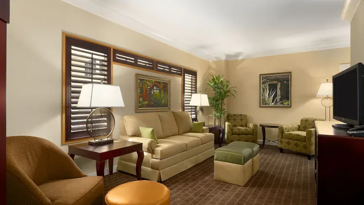 A sofa with 2 ottomans and 2 end tables, 3 chairs, an end table and a dresser with a TV.