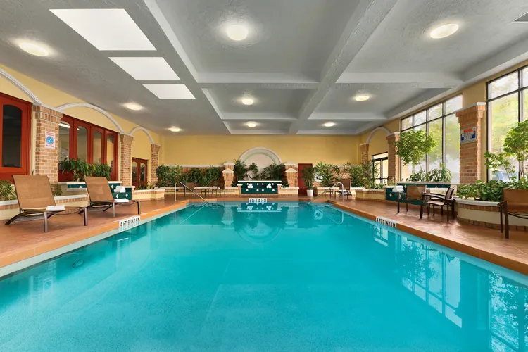 An indoor swimming pool with chairs seating around the water