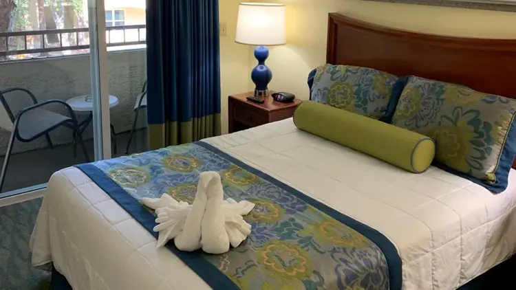 A queen size bed with a swan shaped towel on the bed