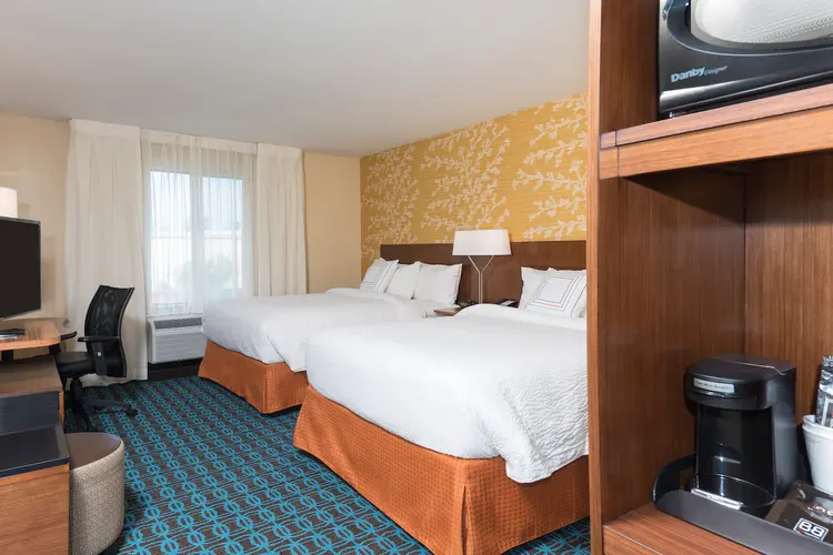 2 queen size beds in a hotel room with a coffee counter, desk, dresser and flat-screen television