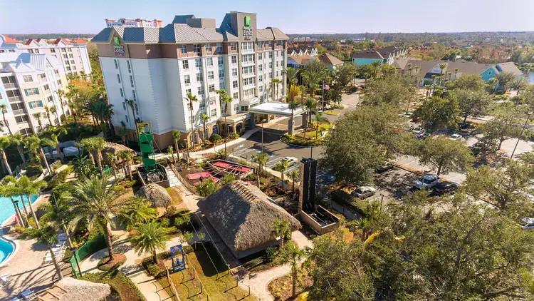 The outside of the Holiday Inn Express & Suites at daytime featuring palm trees and a pool area