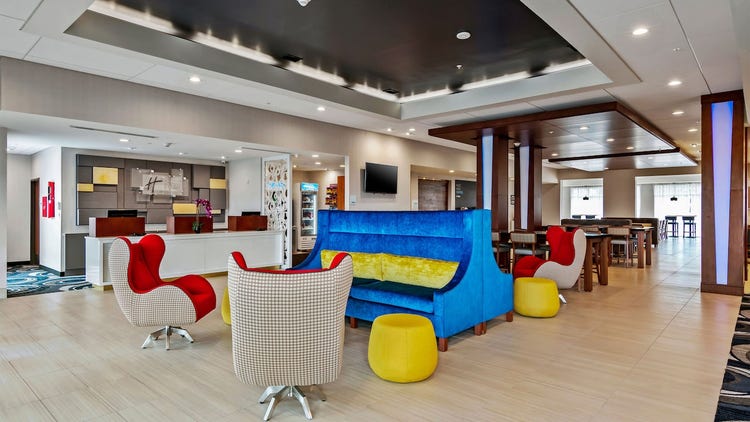 A playfully decorated lobby area with a front desk, couches, swivel armchairs and tables