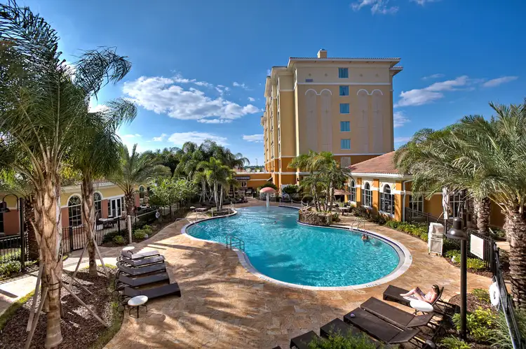 An outdoor pool at Hilton Garden Inn Orlando featuring palm trees and lounge chairs