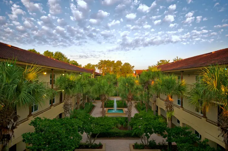 A courtyard featuring palm trees surrounding the resort with a fountain in the center