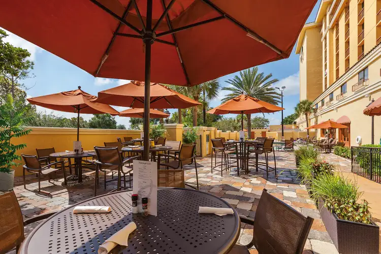 An outdoor seating area on a patio with umbrellas covering the tables and chairs