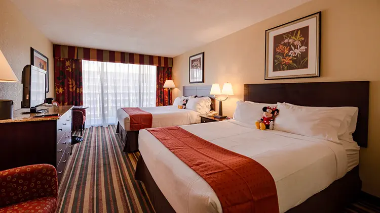 A hotel room featuring 2 large beds, a dresser, flat-screen television and desk space