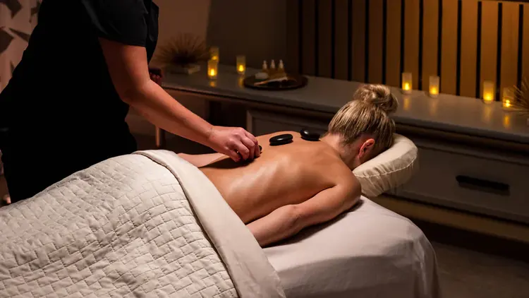 A massage therapist applying hot stones to a Guest’s back