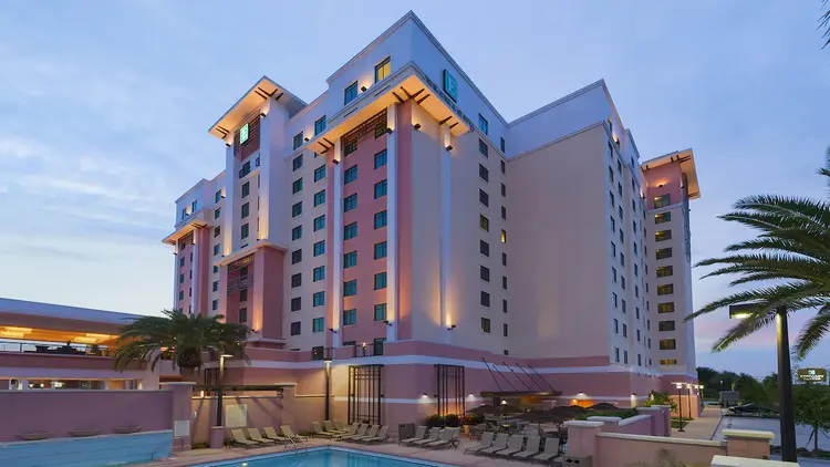 The back of Embassy Suites Lake Buena Vista South, with a patio and a pool with a row of chaise lounges.