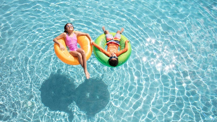 Two young kids laying in inner tubes floating in the pool