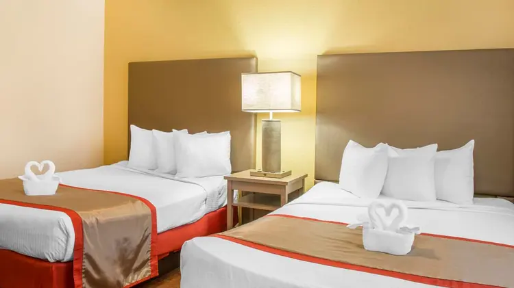 A hotel bedroom featuring 2 full size beds, each adorned with towels folded into swans