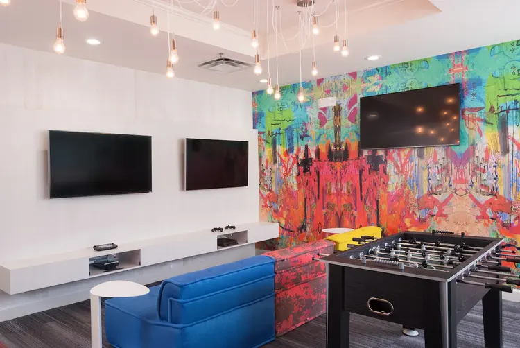 A kids game room features 2 TVs, 2 video game consoles, a sofa and an air hockey table