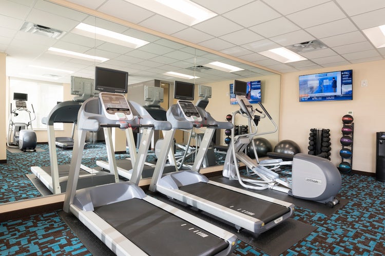 A fitness center featuring treadmills, ellipticals, medicine balls, weights and a workout ball