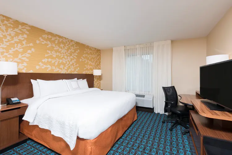 A king size bed in a hotel room featuring a dresser and flat-screen television
