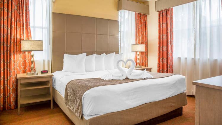 A hotel bedroom featuring a king size bed adorned with towels folded into swans