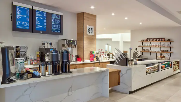 A coffee shop counter with cups, creamers, a tea selection and snacks on display