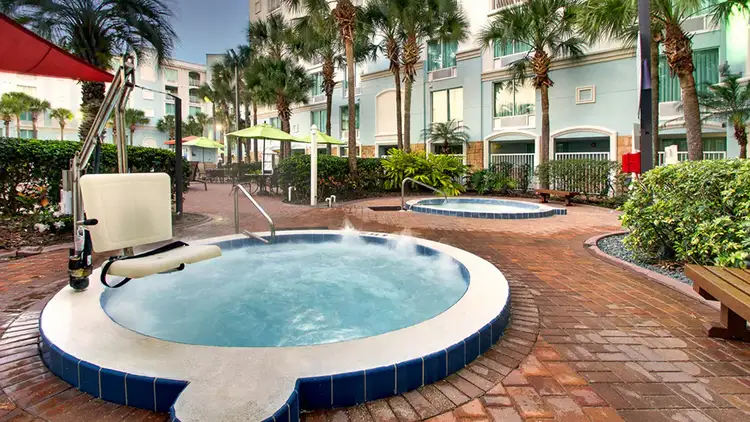 2 hot tubs at the resort pool with one featuring a pool lift chair