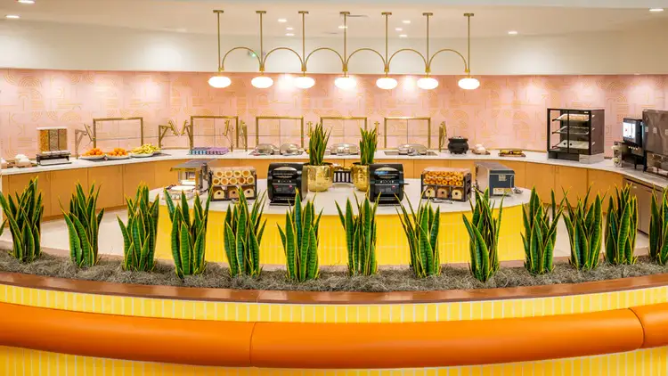A breakfast buffet area with chafing dishes and a waffle station